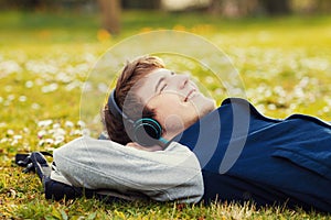 Young student, man relaxing smiling while lying on grass and listening to music.Player.Music,Relax