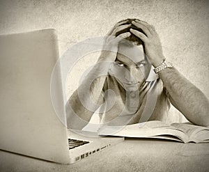 Young student man in stress overwhelmed studying exam with book and computer