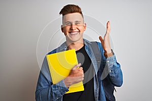 Young student man wearing denim shirt backpack notebook over isolated white background very happy and excited, winner expression