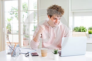 Young student man working and studying using computer laptop screaming proud and celebrating victory and success very excited,