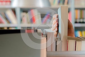 Young student picking a book from the shelf in the library. Preparing for exams, young man searching for or choosing a book in the