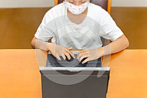 Young student with protective mask hands typing on laptop.