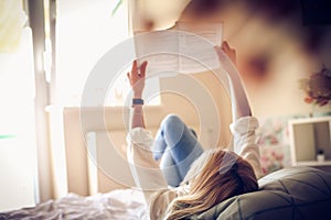 Young student reading a book in bed.