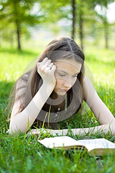 Young student reading book in park