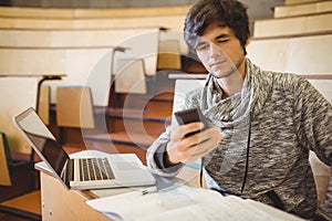 Young student sitting at desk using mobile phone