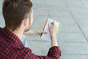 Young student making note, over shoulder shot