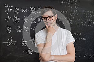 Young student is solving math exam. Mathematics formular on blackboard in background