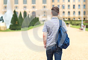 Young student walking to the university. Back view