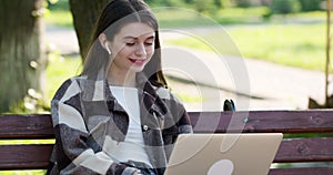 Young student watching lesson online and studying from park. College university student using laptop computer. Studying