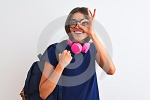 Young student woman wearing backpack glasses headphones over isolated white background with happy face smiling doing ok sign with