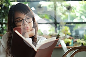 young student woman wearing glasses sitting at library and reading book prepare for exam. image for