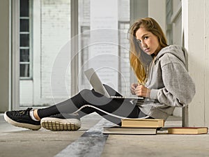 Young student working on her laptop in school hallway