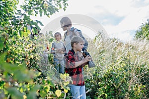 Young students learning about nature, forest ecosystem during biology field teaching class, School boy observing photo