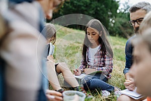 Young students learning about nature, forest ecosystem during biology field teaching class, writing notes. Male teacher