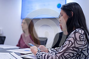 Young students listening the lecture with interest on university, female student using phone