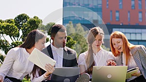 Young students multiracial doing homework in group they using laptops and tablets to studying together they take a sit