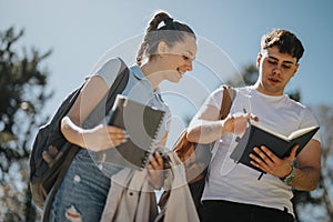 Young students with notebooks studying together in a sunny urban park