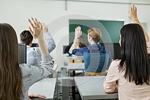 Young students raising hands in a classroom