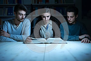Young students reading a book late at night