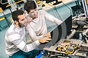 Young students of robotics preparing robot for testing