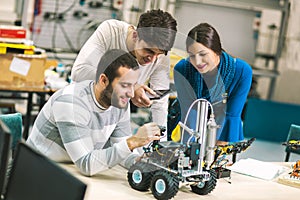 Young students of robotics preparing robot for testing