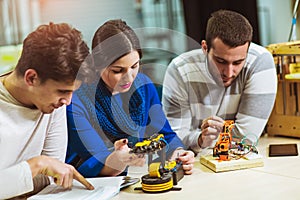 Young students of robotics preparing robot for testing