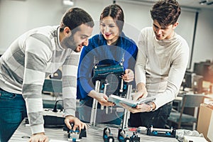 Young students of robotics preparing robot for testing