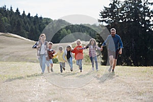 Young students running across meadow during biology field teaching class, holding hands. Dedicated teachers during