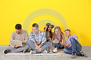 Young students sitting on floor near color wall