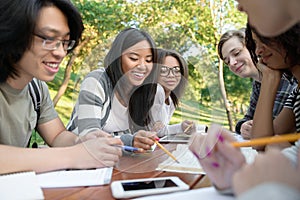 Young students sitting and studying outdoors while talking
