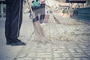 Young students sweeping dried leafs on the floor in school
