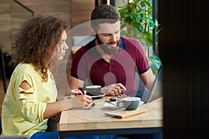Young students working using laptop, working in restaurant.
