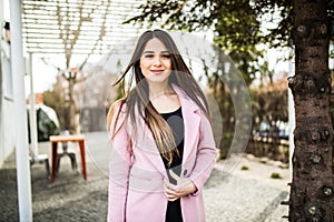 Young stylish beautiful woman walking in street, wearing pink coat