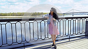 Young stylish brunette put sunglasses on face and enjoys beautiful river view