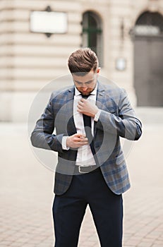 Young stylish businessman adjusting his suit, neck tie