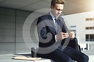 Young stylish businessman while using his phone