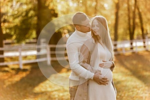 Young stylish couple lovers are hugging and kissing in the autumn park. Lovely romantic moment between man and woman in