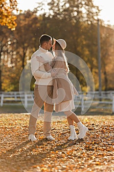 Young stylish couple lovers are hugging and kissing in the autumn park. Lovely romantic moment between man and woman in