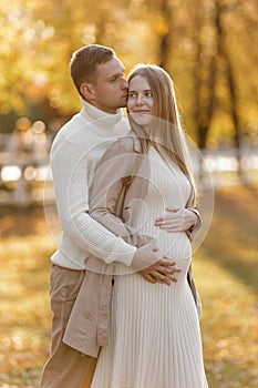 Young stylish couple lovers are hugging and kissing in the autumn park. Lovely romantic moment between man and woman in