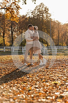 Young stylish couple lovers are hugging and kissing in the autumn park. Lovely romantic moment between man and woman in