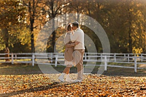 Young stylish couple lovers are hugging and kissing in the autumn park. Lovely romantic moment between man and woman in