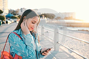 Young, stylish and elegant woman browsing phone on a beautiful day. Peaceful, stressless and smiling female on a beach