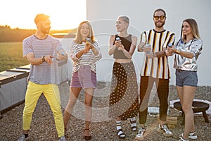 Young stylish friends celebrating on the rooftop at sunset