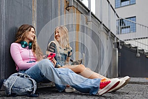 Young stylish generation Z girls studying together outdoors after school.