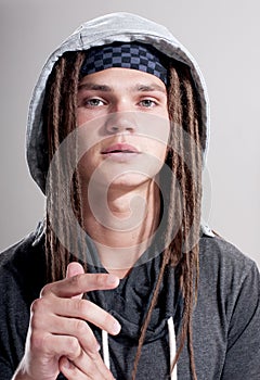 Young stylish guy with dreadlocks and wearing a hood.