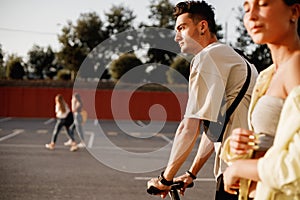 Young stylish guy and girl are walking together on the square for parking on the sunny day