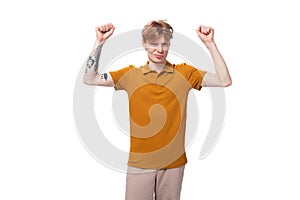a young stylish guy with red hair is dressed in a mustard-colored T-shirt is experiencing joy