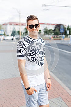 Young stylish guy in sunglasses, T-shirt and shorts