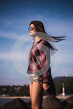 Young stylish happy hipster woman traveling around the world wearing aviator sunglasses, denim shirt, tropical island