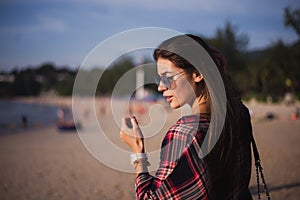 Young stylish happy hipster woman traveling around the world wearing aviator sunglasses, denim shirt, tropical island